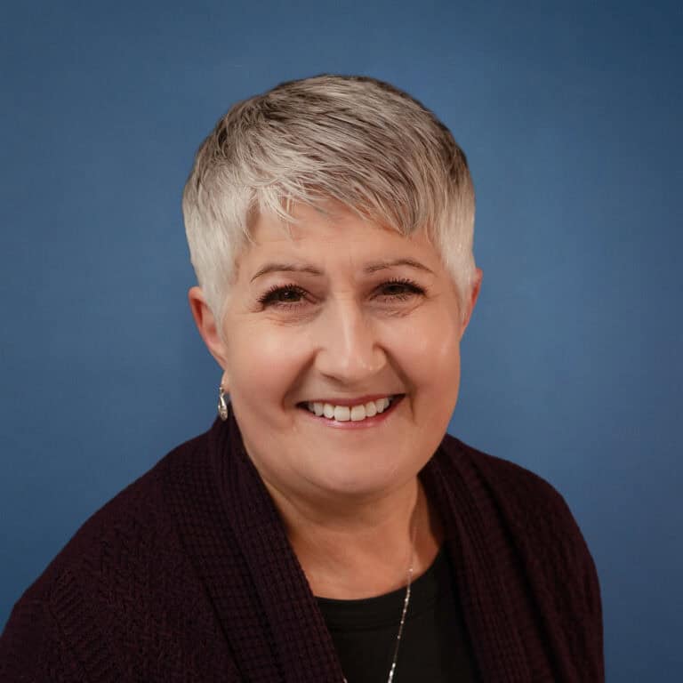 Portrait of Leslie Crane smiling warmly at the camera.