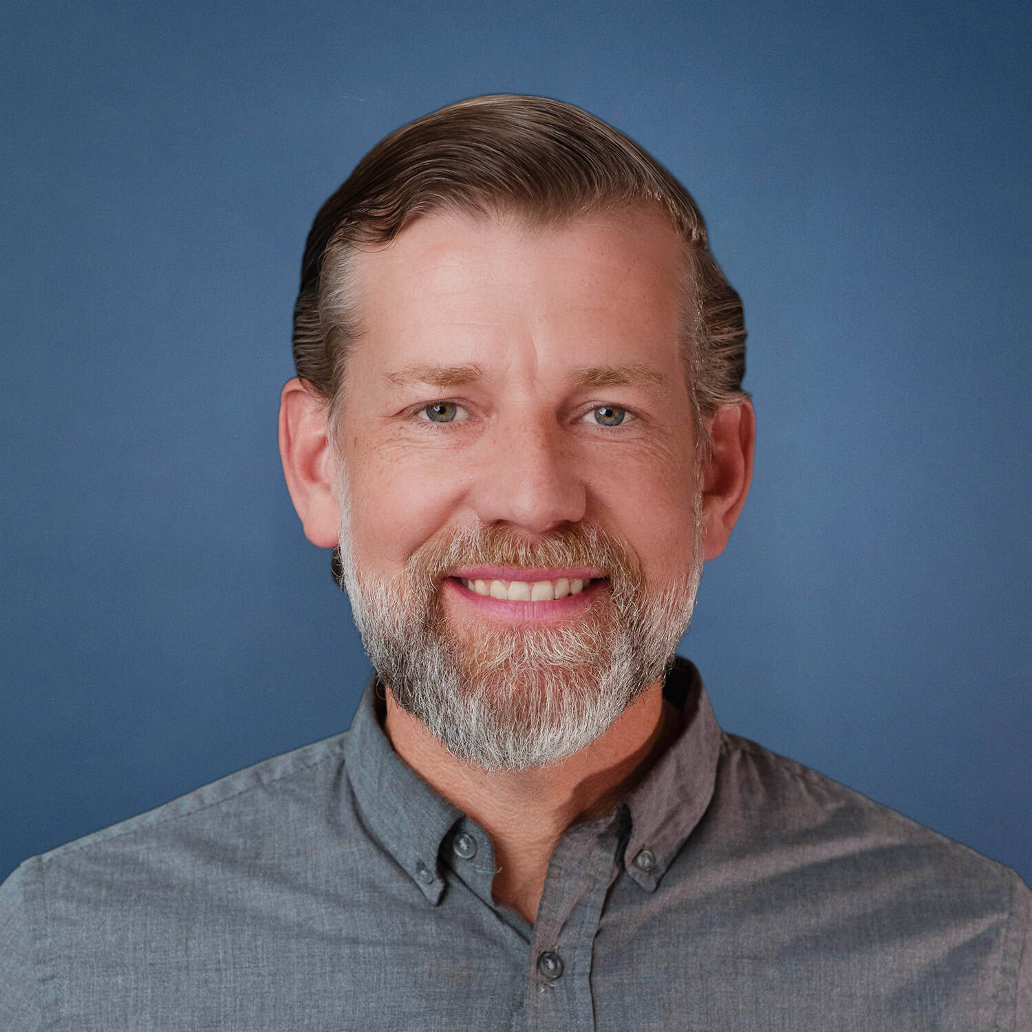 Nathan Miller smiling in a gray shirt with a blue background.