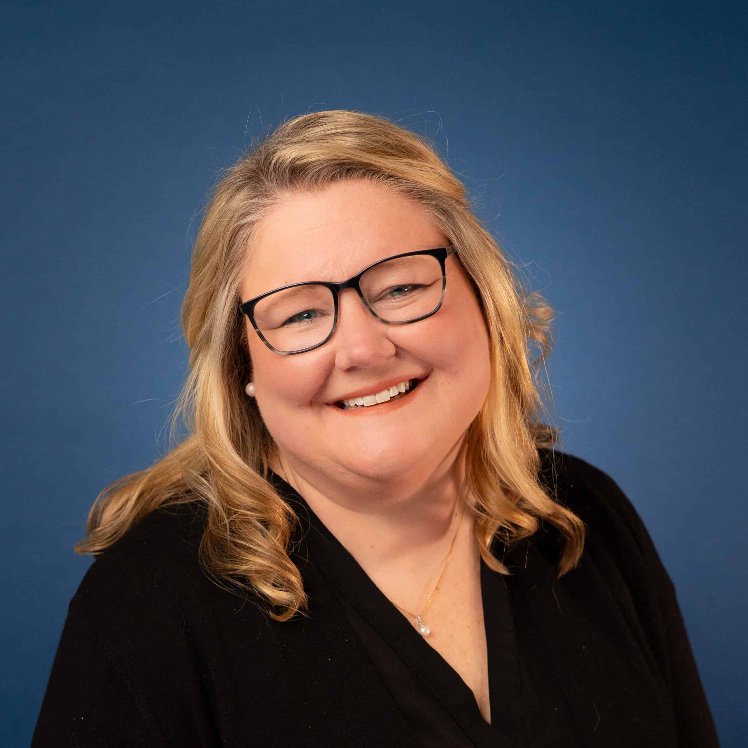 Kaci Calhoun smiles in a professional headshot against a blue background.