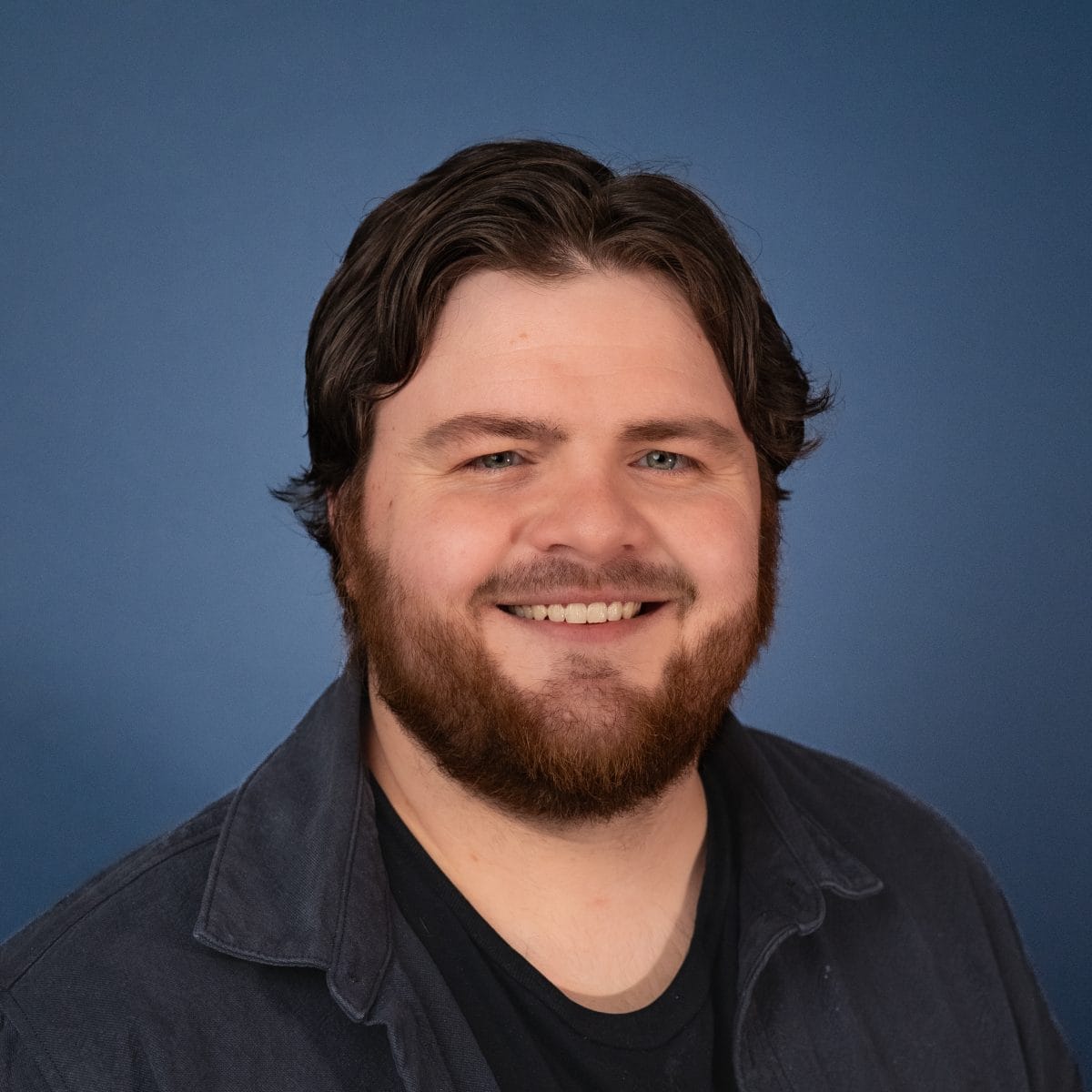 Headshot of Taylor Fair smiling against a blue background.
