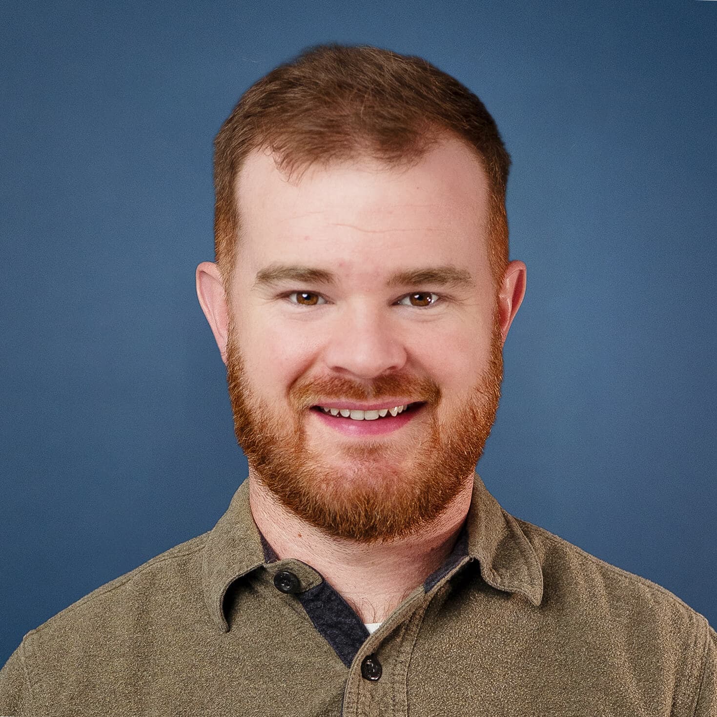 Caleb Jenkins smiling in a headshot with a beard and brown shirt against a blue background.