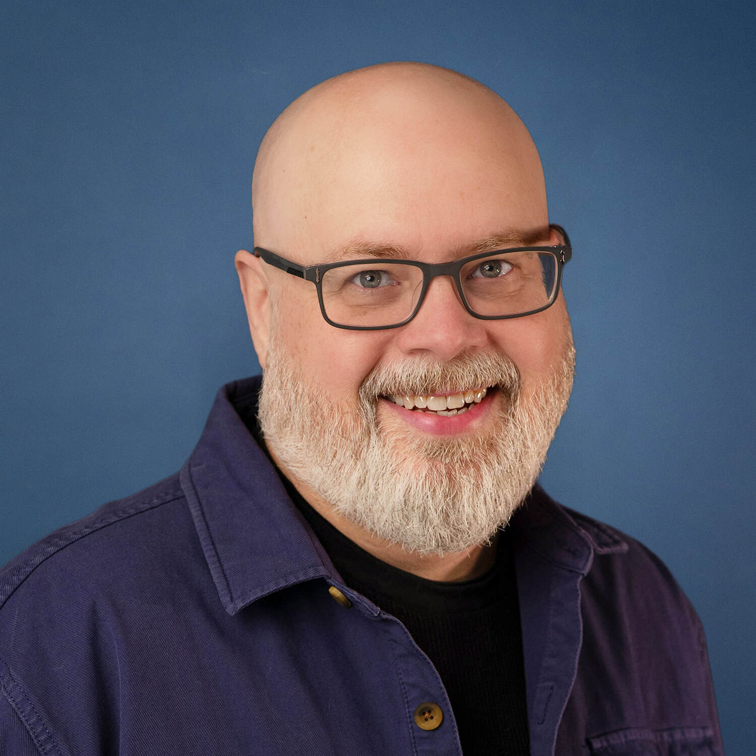 Randy Bonifield, bald man with glasses and a beard, smiling against a blue background.