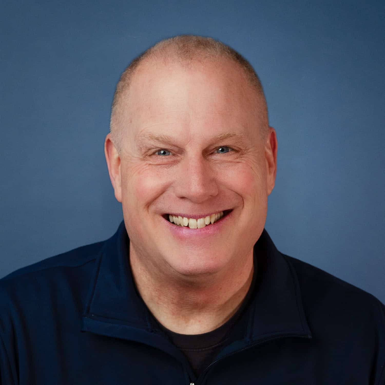 Alan Mercer smiles in a headshot with a blue background.