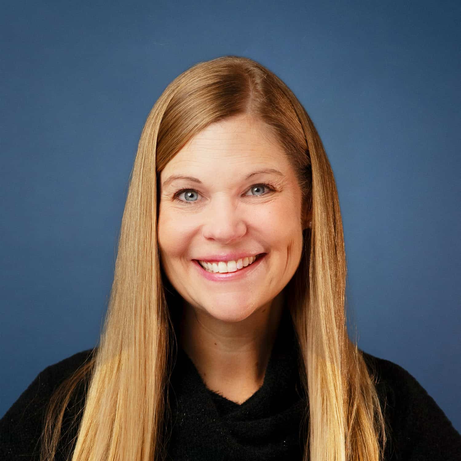 Portrait of Carolyn Poage smiling against a blue background.