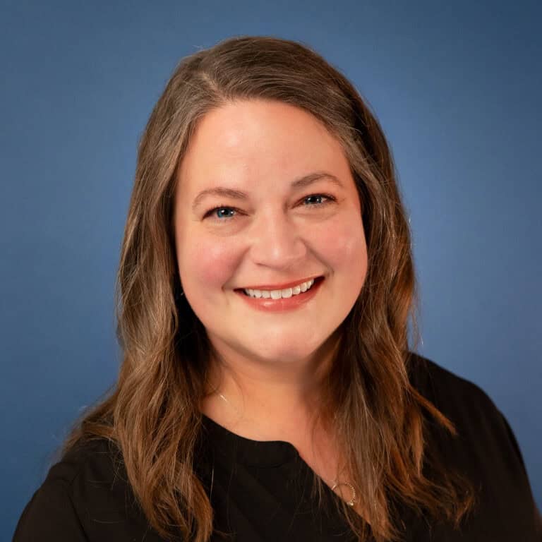Sharla Pair smiling in a headshot with a blue background.