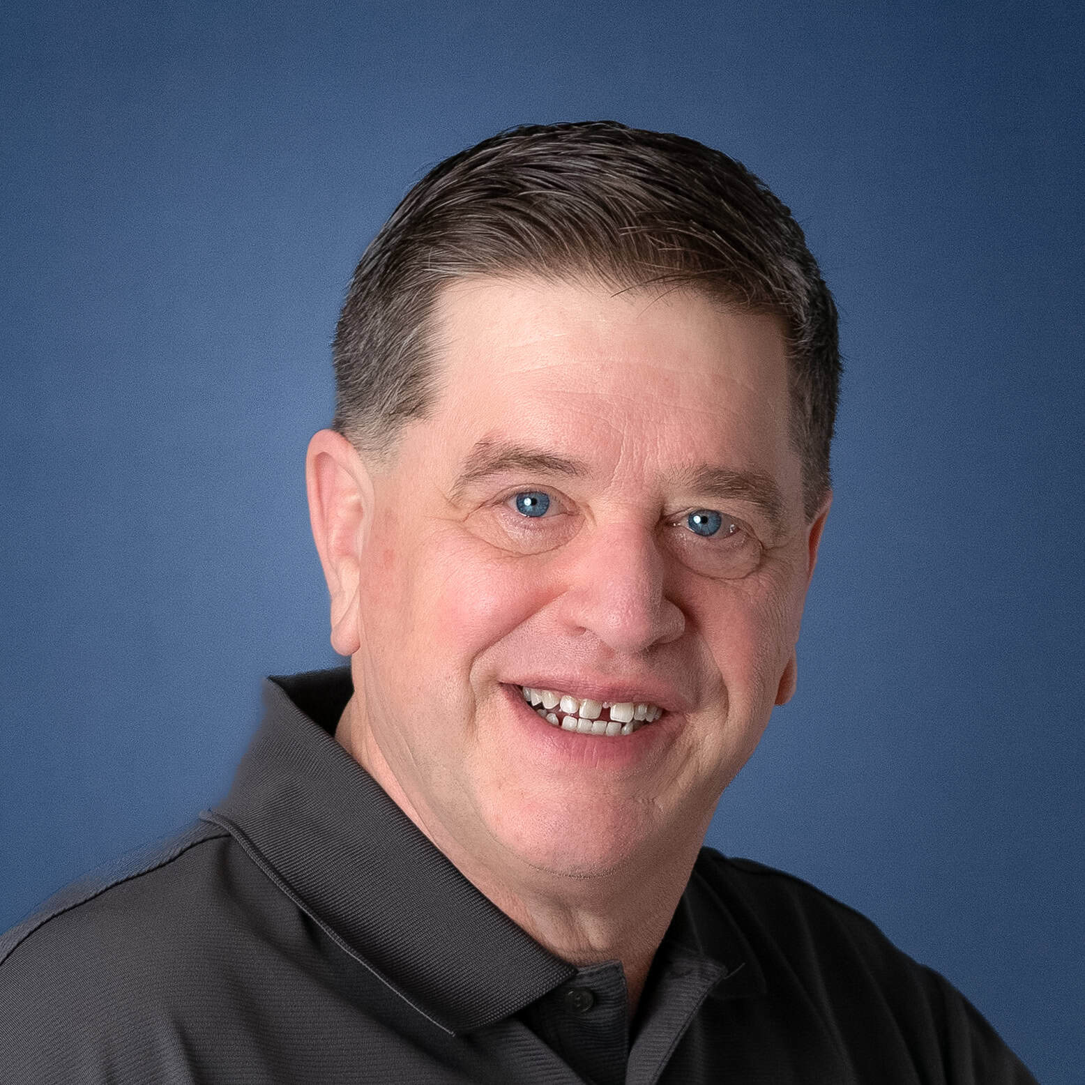 Headshot of Dean Parker smiling against a blue background.
