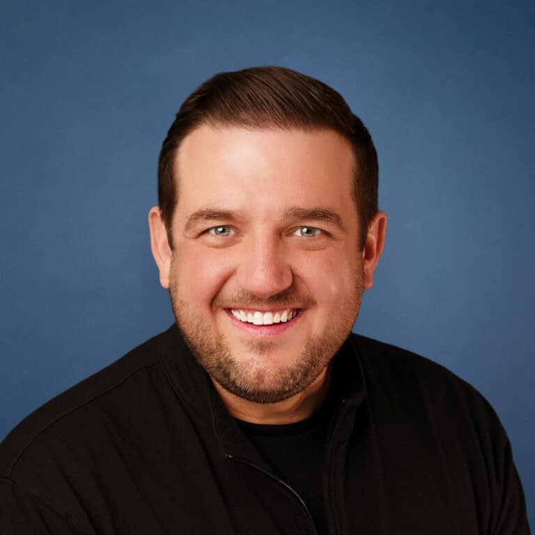 Paul Brandes headshot with a friendly smile against a blue background.