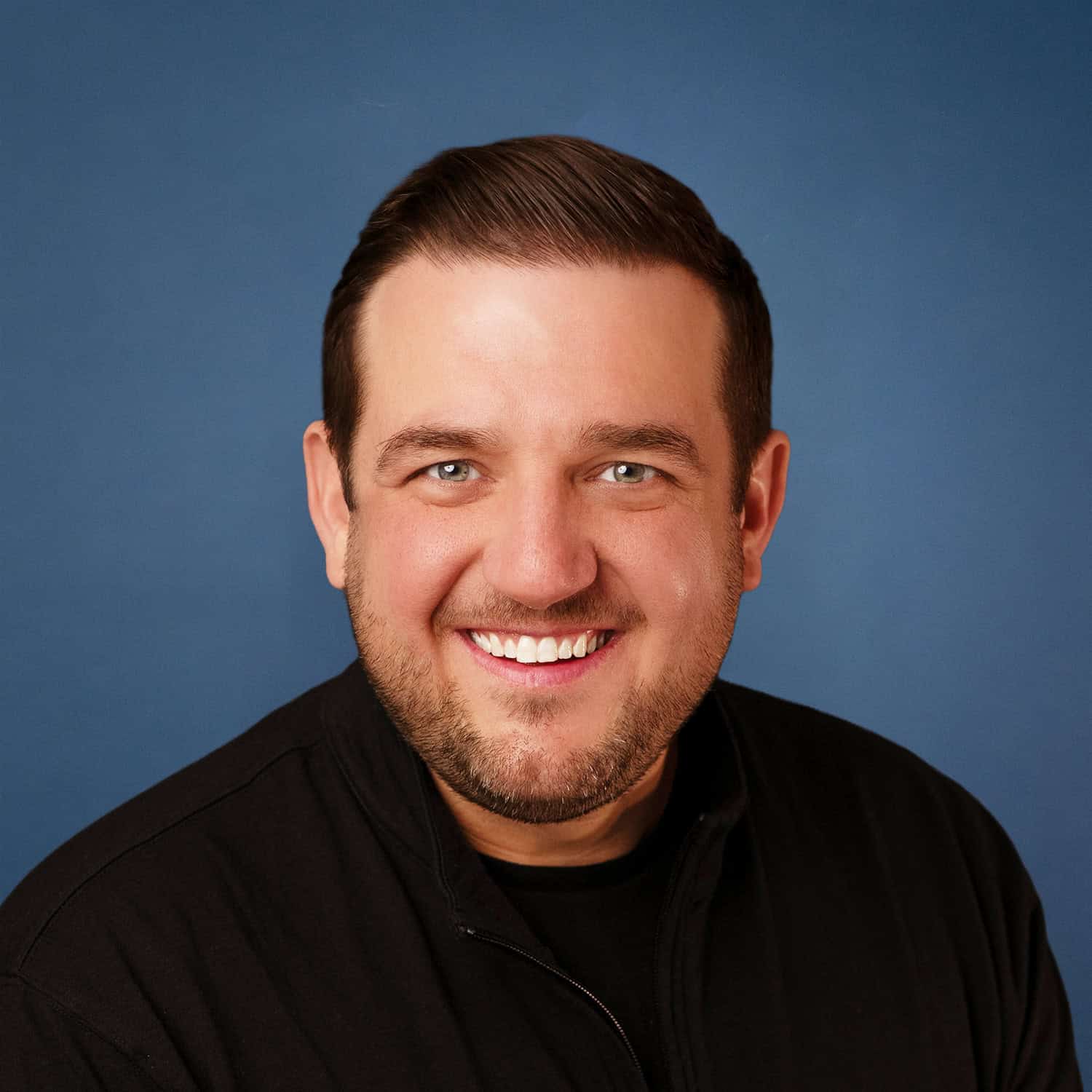 Paul Brandes headshot with a friendly smile against a blue background.