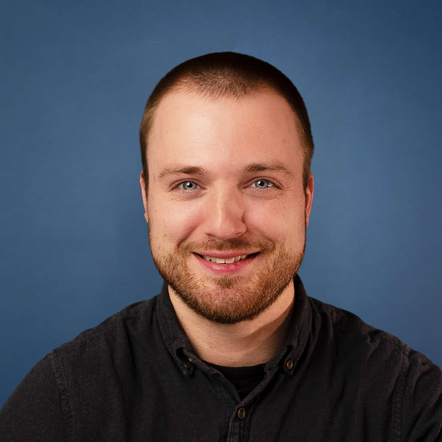 Headshot of Brooks Nesse smiling against a blue background.