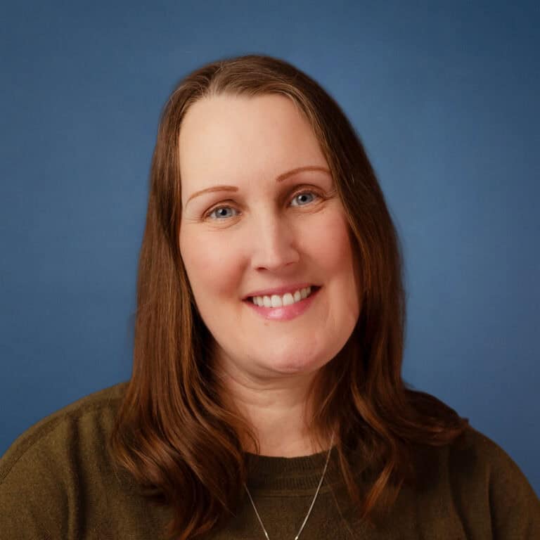 Bethany Hininger smiles in a professional headshot with a blue background.
