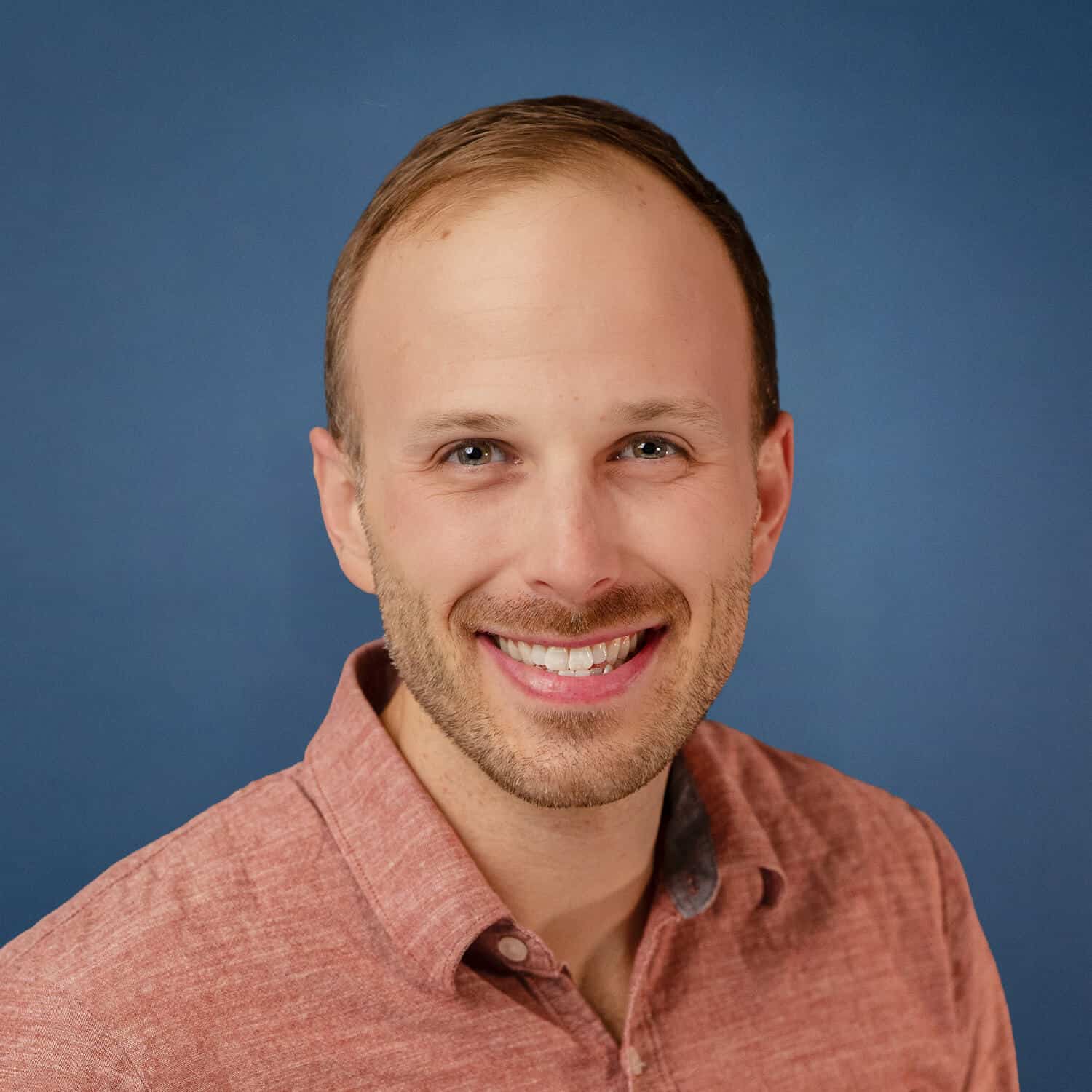 Headshot of Brent Bovitz smiling against a blue background.
