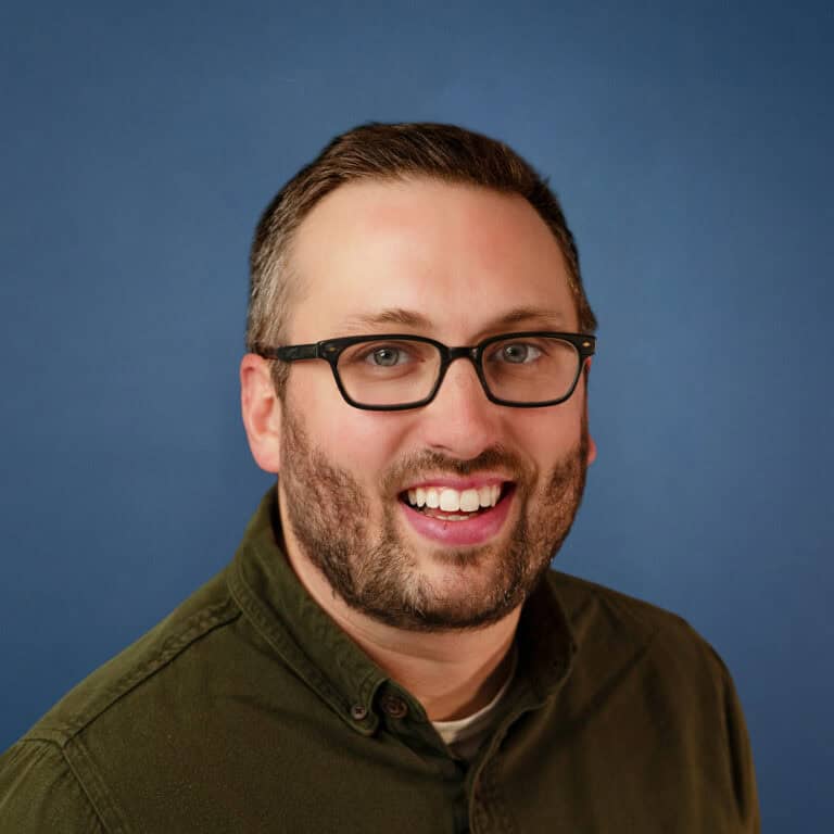 Headshot of Jacob King smiling, wearing glasses and an olive green shirt.