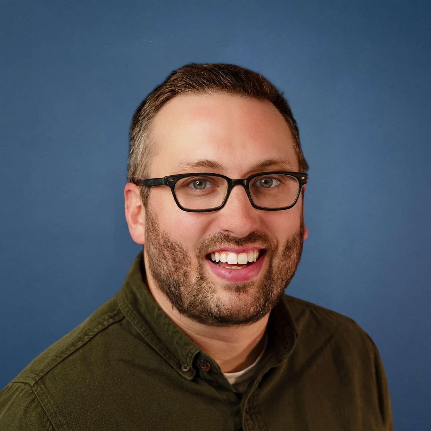 Headshot of Jacob King smiling, wearing glasses and an olive green shirt.
