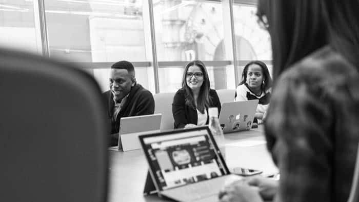 Team collaborating on laptops in a modern office setting.