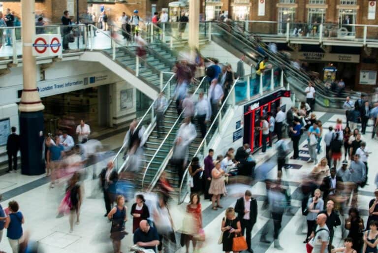 Blurred motion of people walking in a busy London train station.