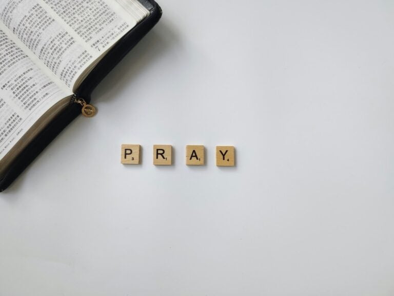 Open Bible with "PRAY" spelled out in wooden blocks. Pray More, Worry Less.