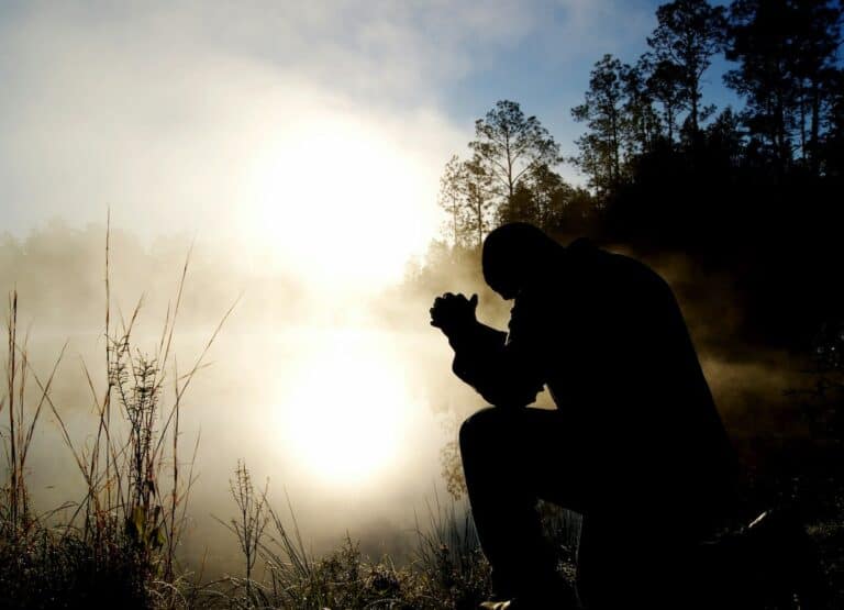 Silhouette of a man kneeling in prayer by a misty lake, reflecting on "The Forgetful Prophet.