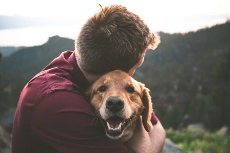 Man hugging his golden retriever dog outdoors, a symbol of God's love.