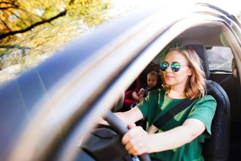 Woman driving car with baby in car seat. Safe driving.