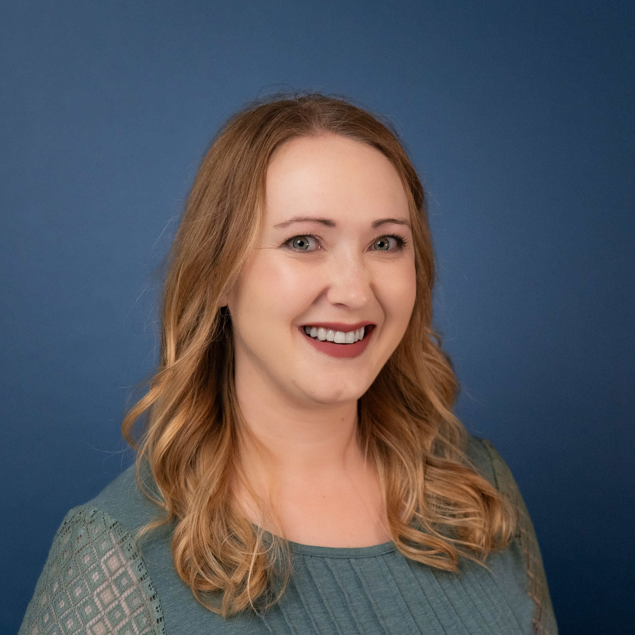 Kate Heidenreich smiles in a portrait with a blue background.