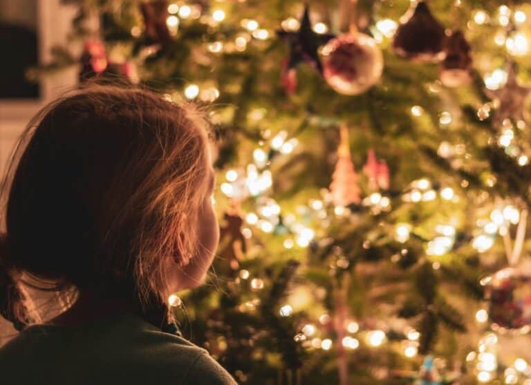 Child gazes at a brightly lit Christmas tree during Advent.