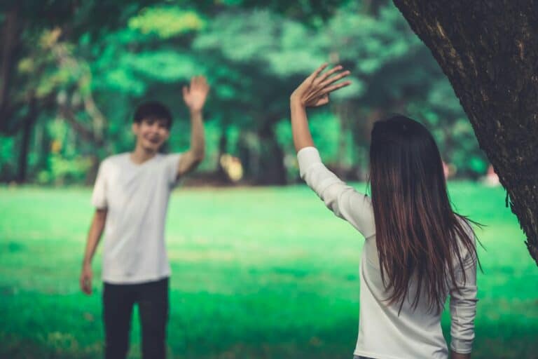 Two people waving at each other in a park, symbolizing relationships and finishing well.