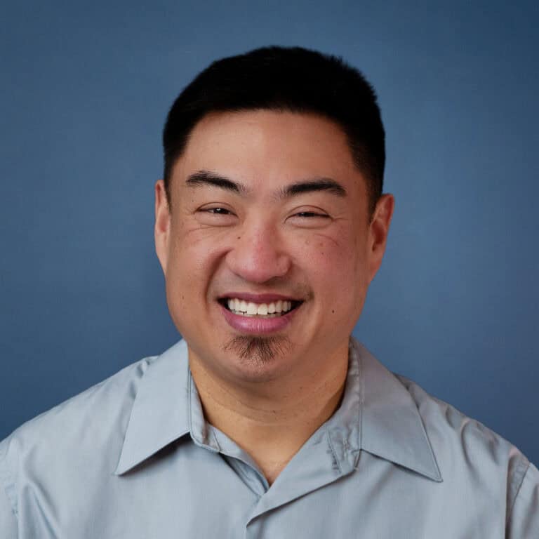 Smiling headshot of Austin Szu against a blue background.