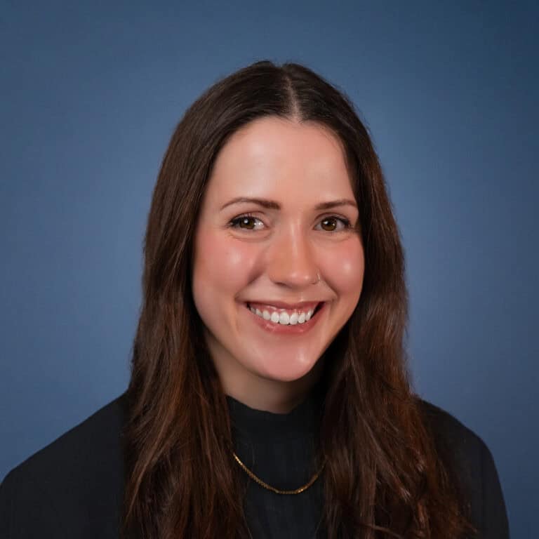 Portrait of Rebekah Martin-Smither smiling with a blue background.