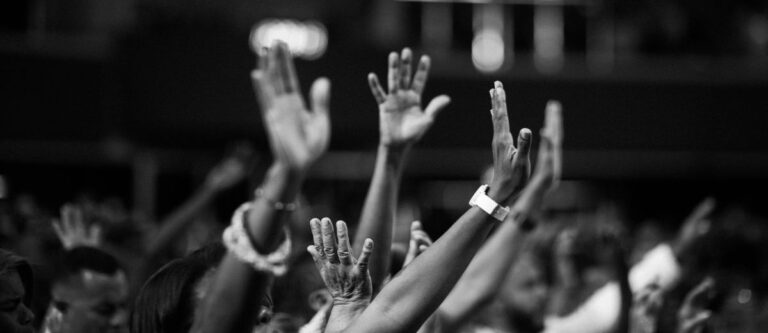 People raising hands during a church service, potentially expressing faith or worship.