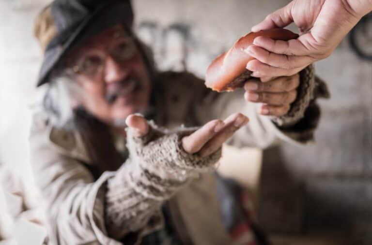 Hand offering food to a homeless man, showing virtue