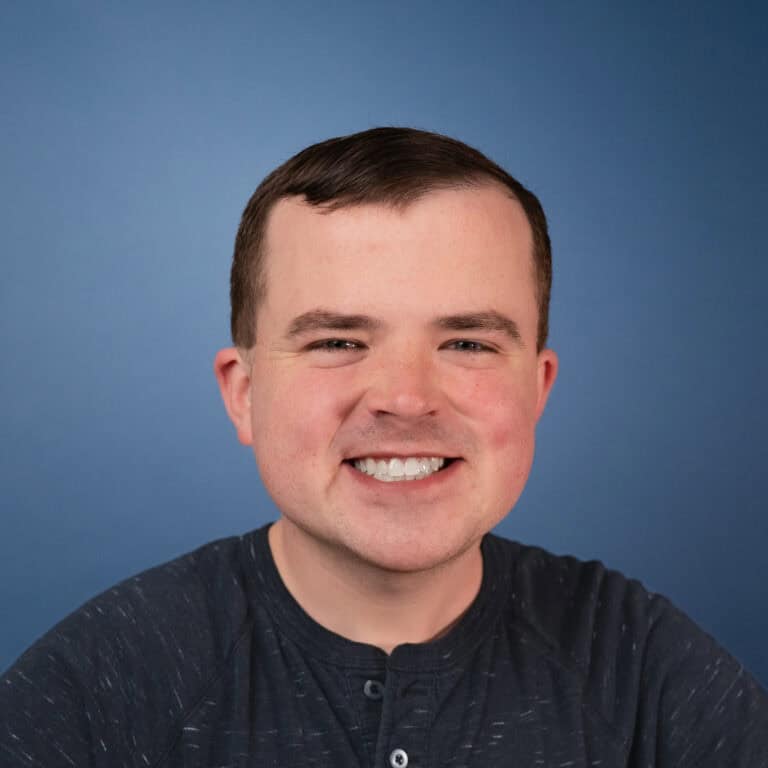 Headshot of Joshua Freerksen smiling against a blue background.