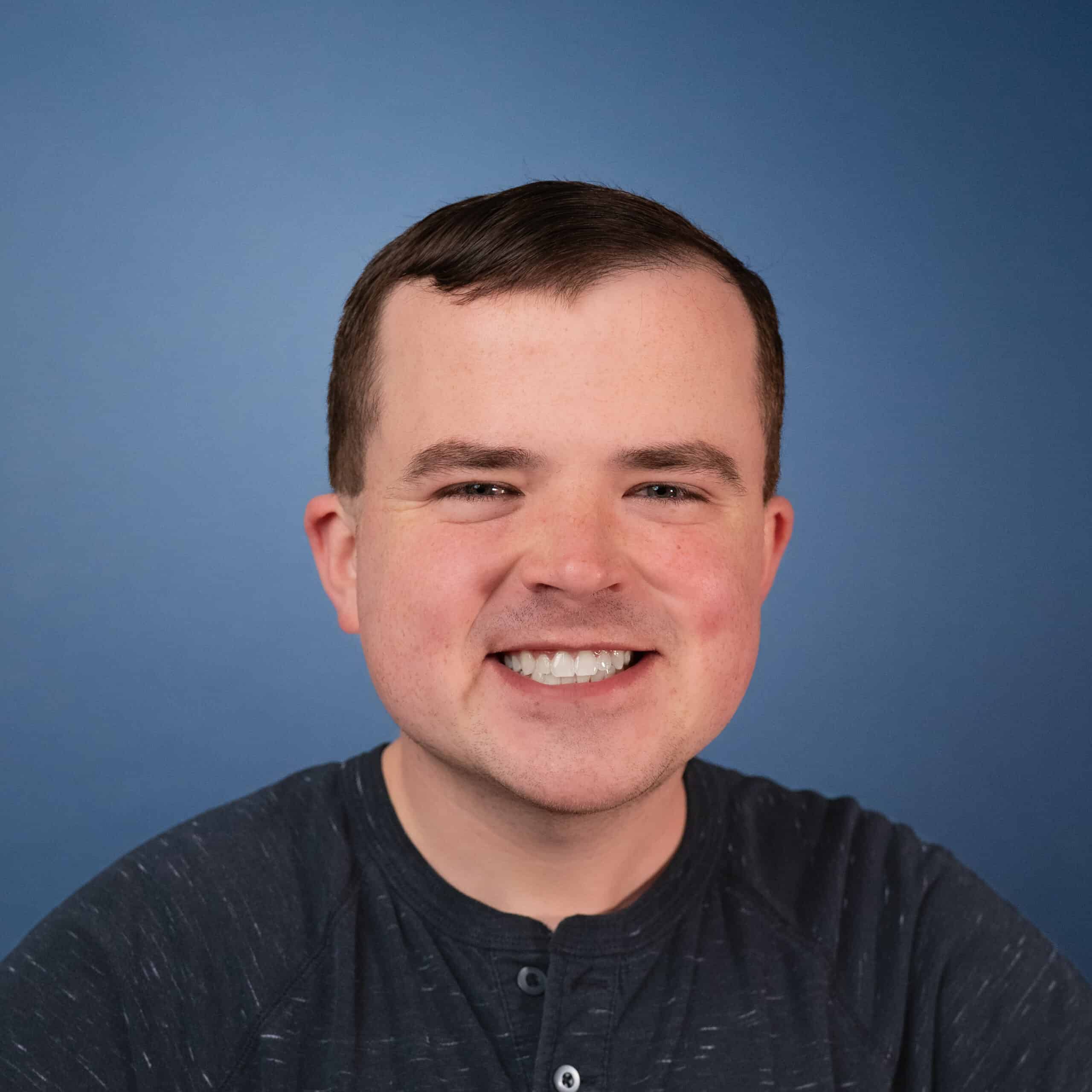 Headshot of Joshua Freerksen smiling against a blue background.