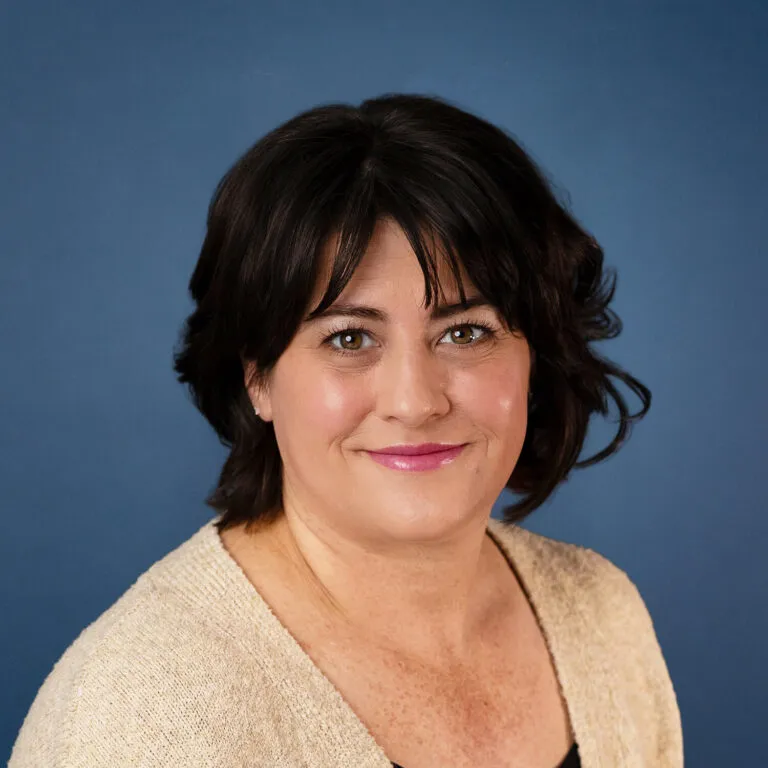 Meghan Adams, smiling woman with dark hair wearing a beige cardigan.