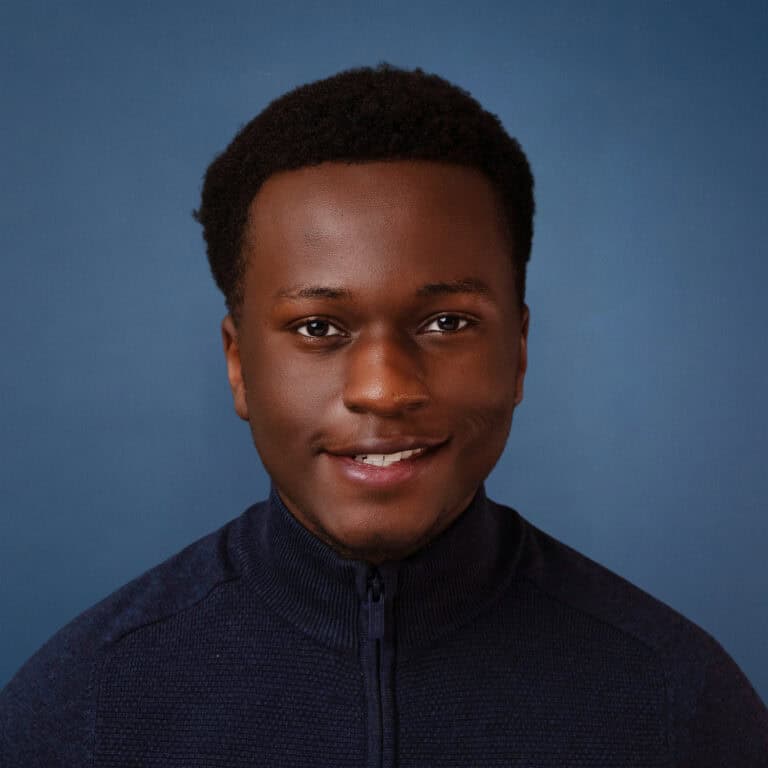Portrait of Shawn Njoroge smiling, wearing a dark blue sweater.