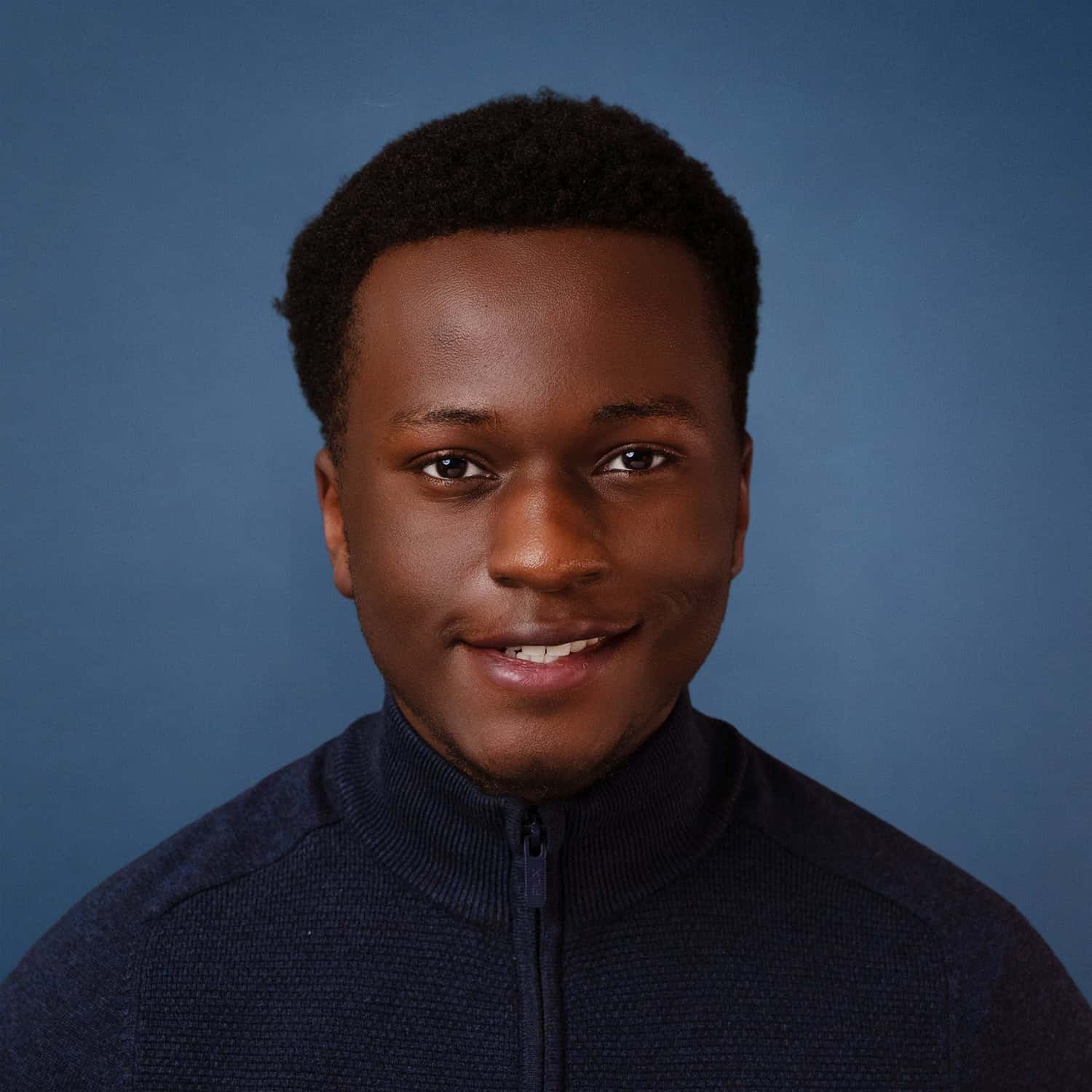 Portrait of Shawn Njoroge smiling, wearing a dark blue sweater.