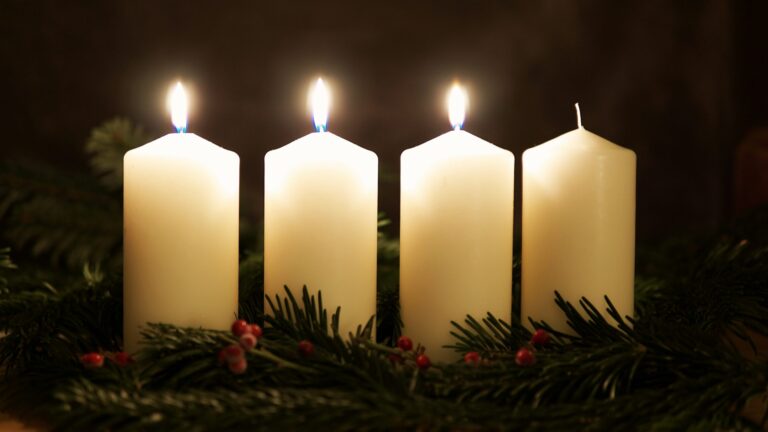 Advent wreath with three lit candles, symbolizing joy in the Gospel.