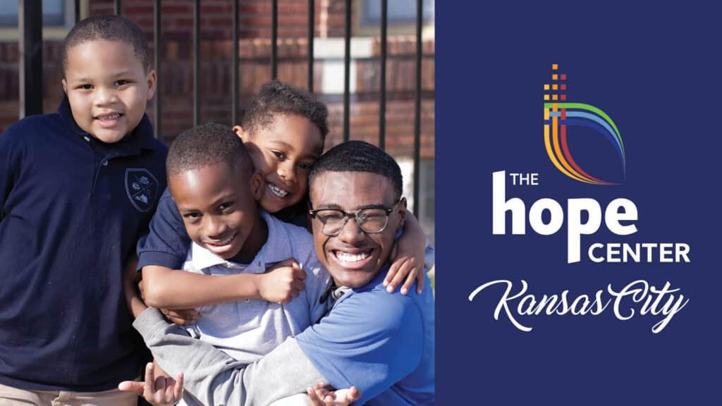 Four smiling boys hugging, representing The Hope Center Kansas City's outreach programs.