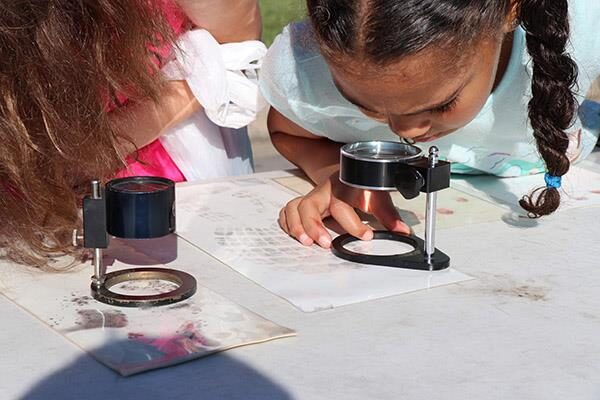 Kids using magnifying glasses to examine prints outdoors. Outreach activity.
