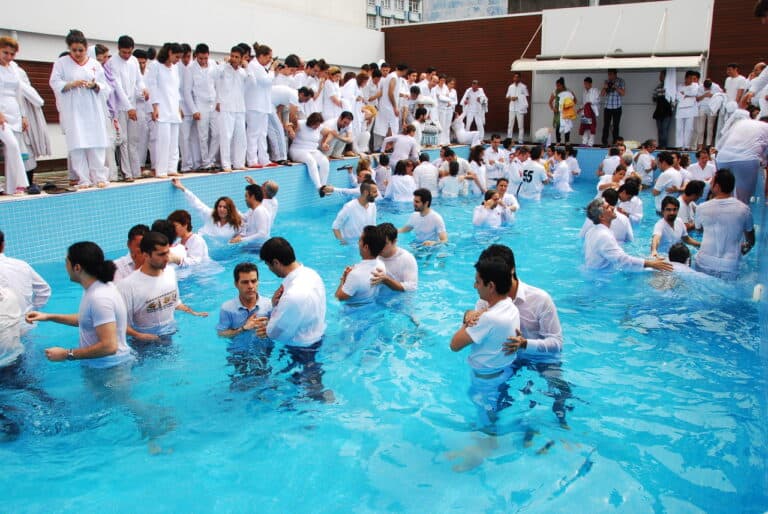 Baptism ceremony in a pool with many people wearing white robes, Christ Community Church.
