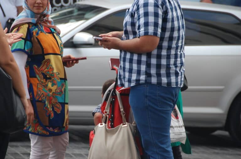 People interacting, possibly doing outreach, with a child and stroller visible.