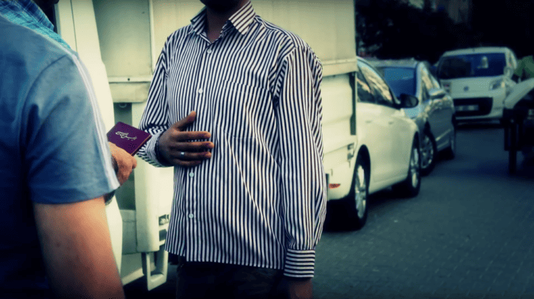 Man in striped shirt holding passport during an outreach event.