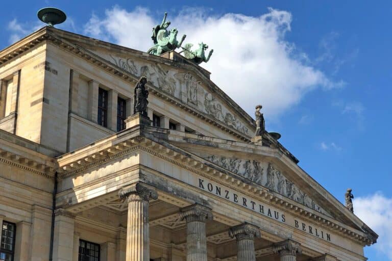 Konzerthaus Berlin architecture with statues and a chariot sculpture against a blue sky.