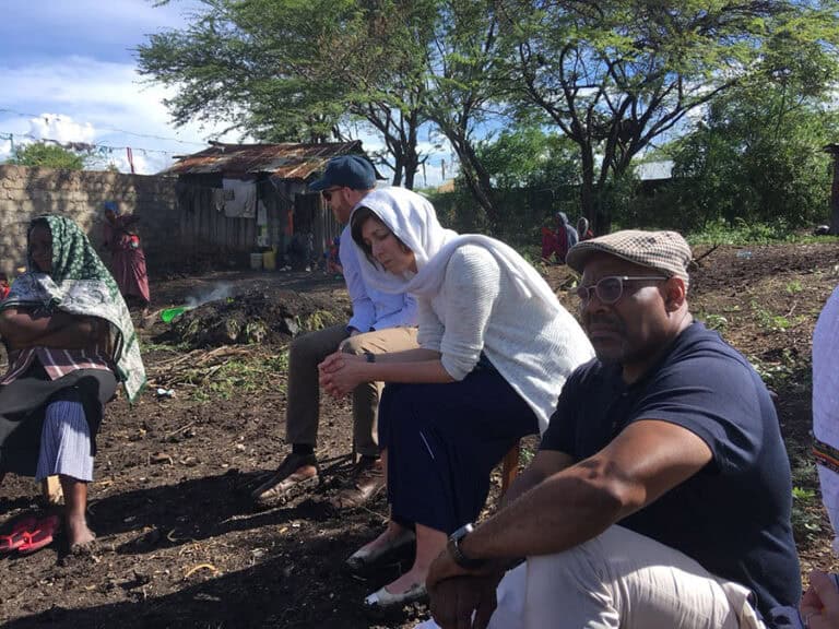 People sitting outdoors in a community outreach setting.