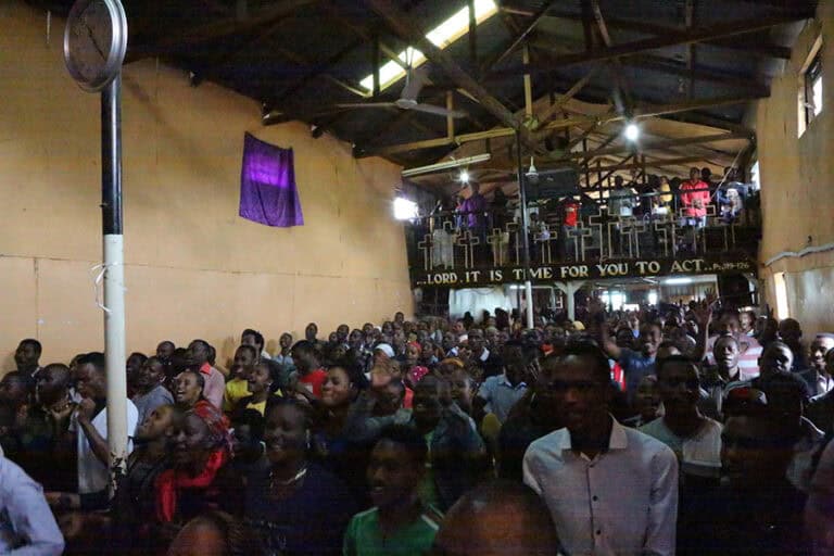 Congregation at church service, banner reads 