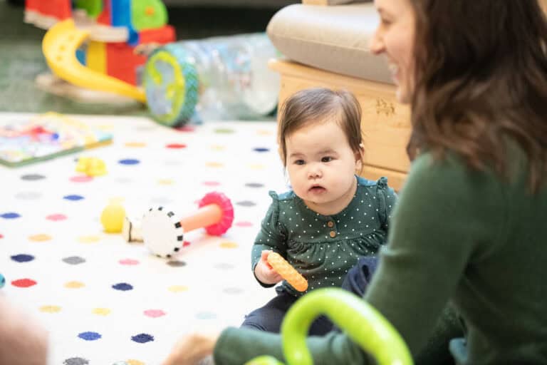 Baby playing with toys on a colorful polka dot rug at Downtown Campus.