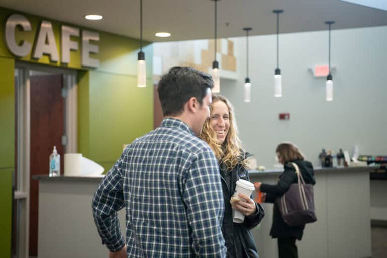People chatting at the Leawood Campus cafe, holding coffee.