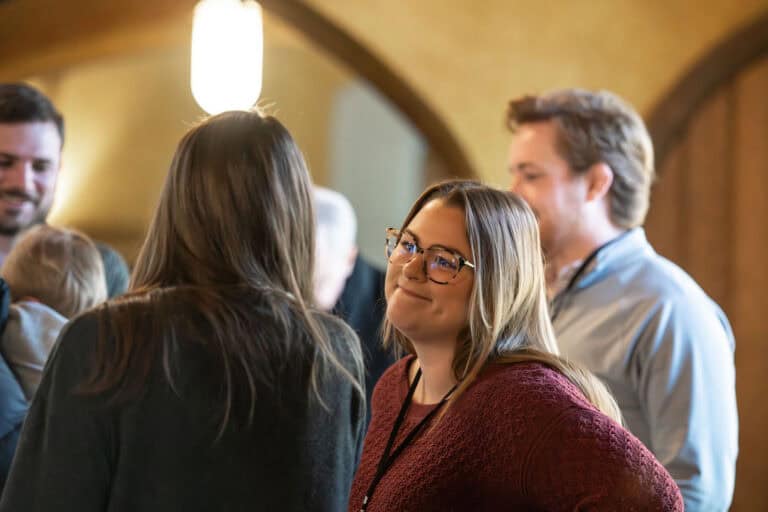 Woman smiling at Outreach event, surrounded by people.