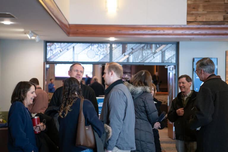 People gathering at Christ Community Church's Leawood Campus, socializing in a bright, modern lobby.