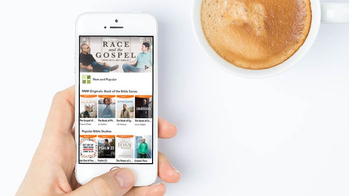 Hand holding a phone displaying the RightNow Media app with Bible study resources.