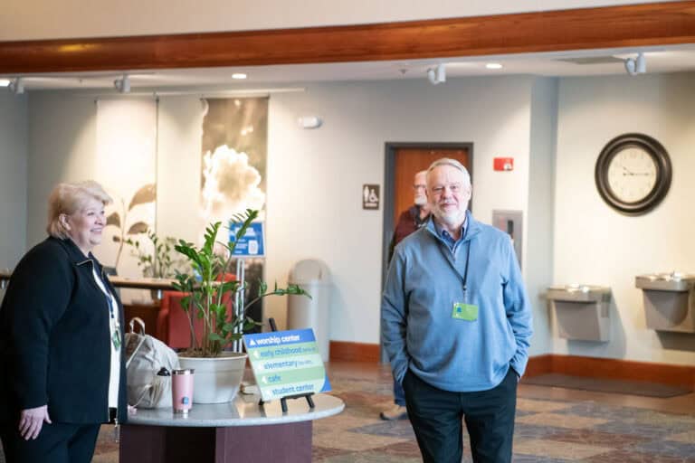 People at Christ Community Church lobby, sign for worship center visible.